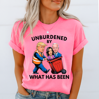 Woman wearing pink shirt with cartoon Trump pushing Biden and Kamala in trash bin – “Unburdened By What Has Been” text