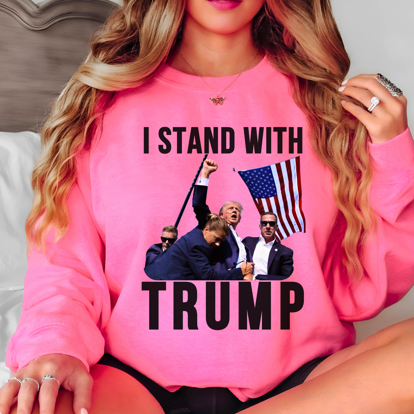 Woman wearing “I Stand With Trump” sweatshirt in bright pink with American flag – patriotic apparel
