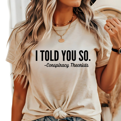 Woman wearing “I Told You So - Conspiracy Theorists” shirt in sand