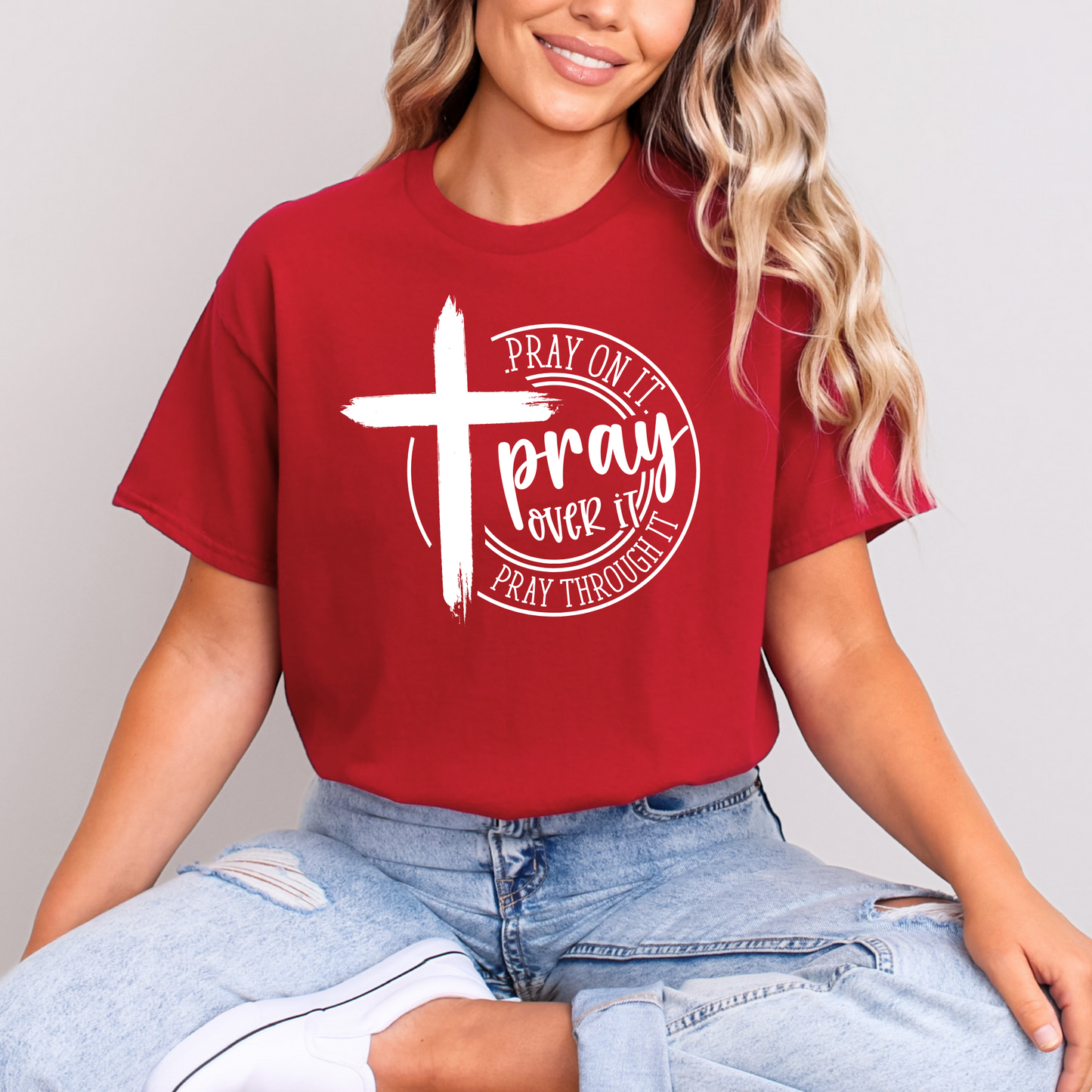 Person wearing a red t-shirt with a white cross and text design on a plain background