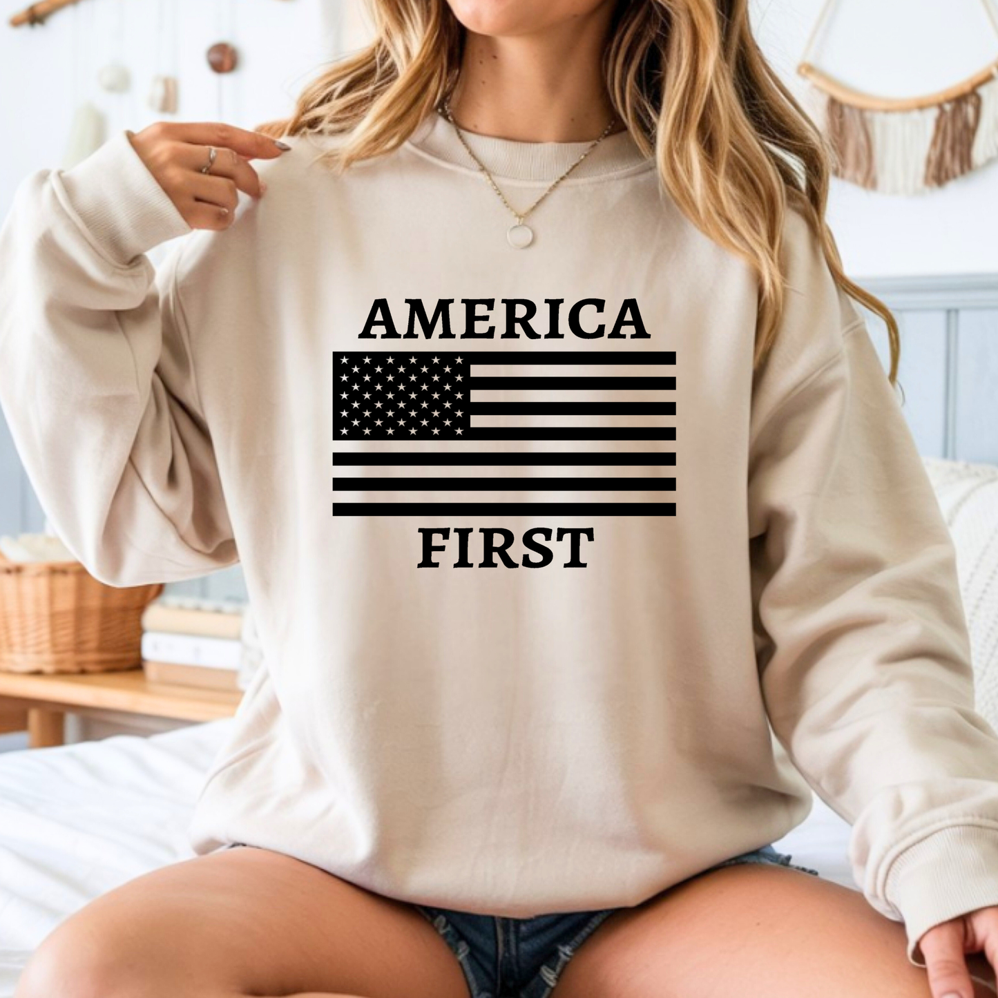 Woman wearing a beige sweatshirt with 'AMERICA FIRST' and an American flag design.