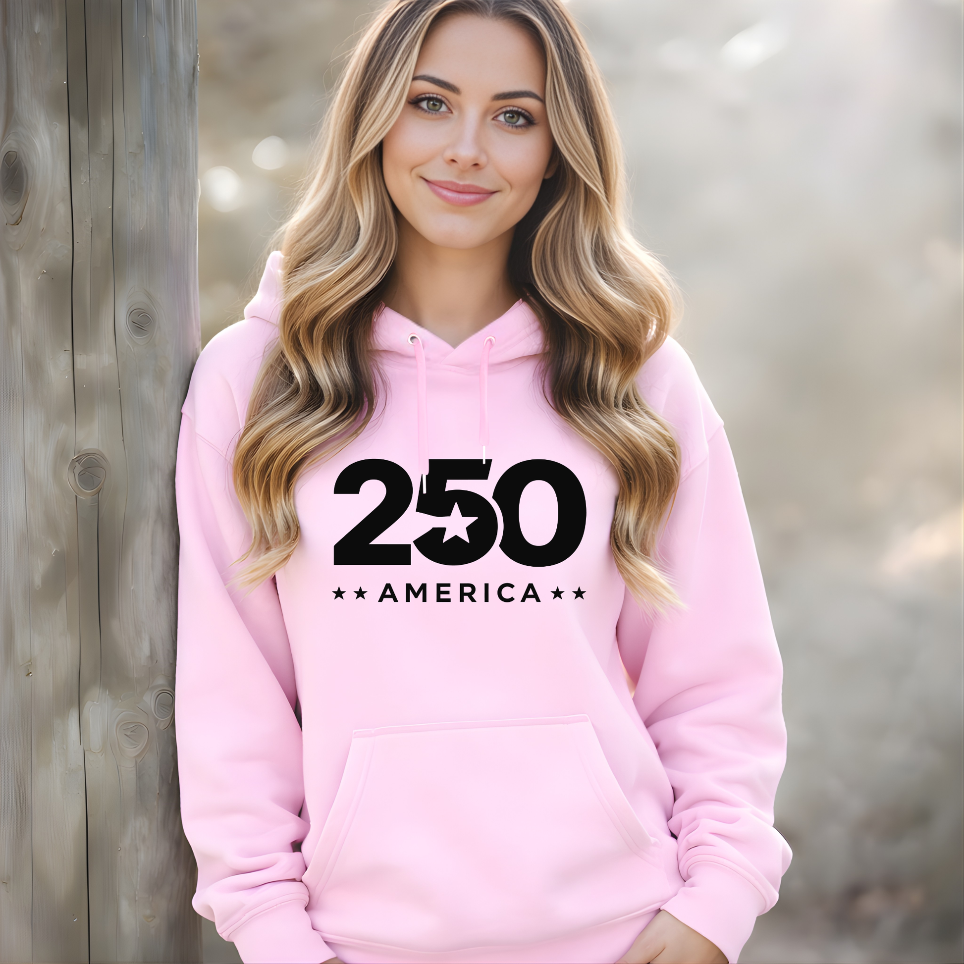 Woman wearing a pink hoodie with '250 America' text against a wooden background