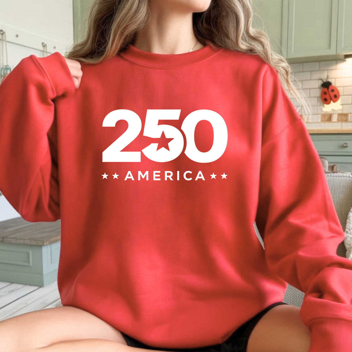 Woman wearing a red sweatshirt with '250 America' printed on it in a kitchen setting.