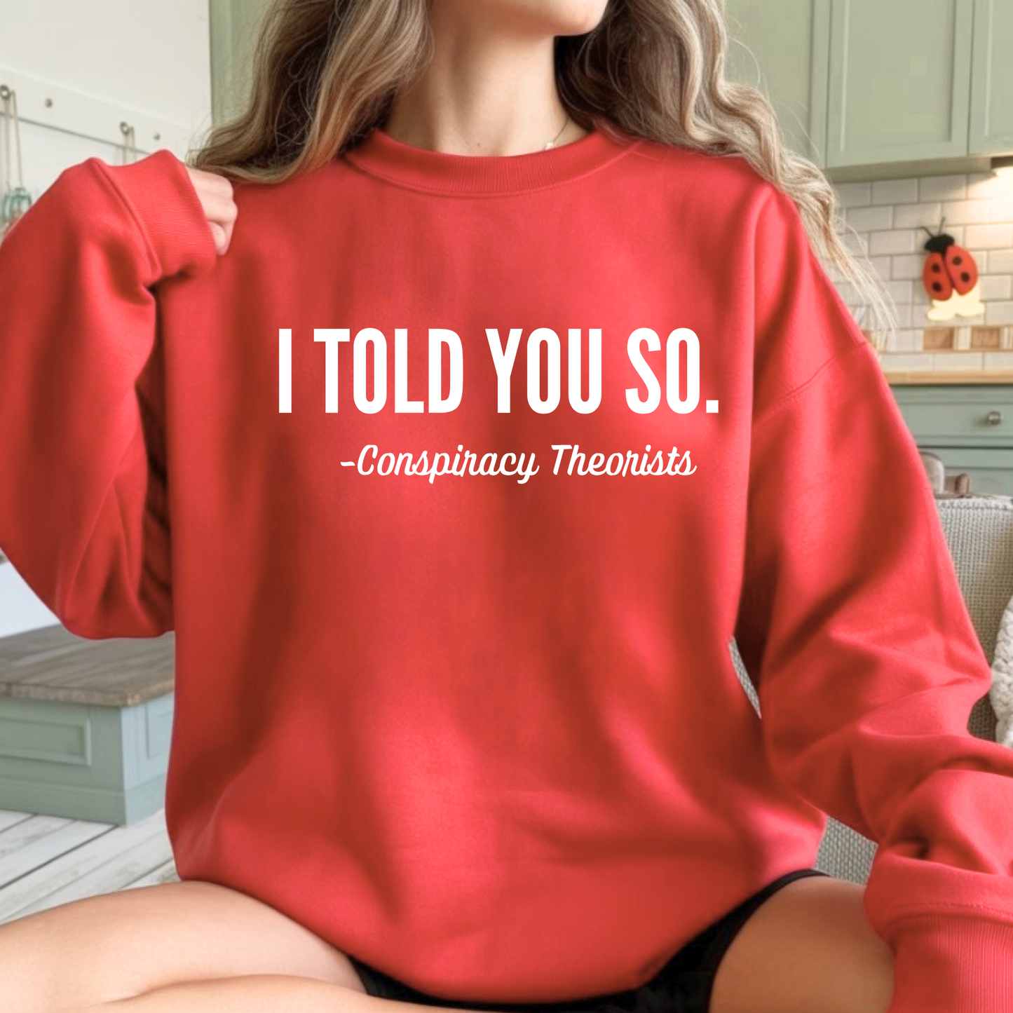 Woman wearing a red sweatshirt with 'I Told You So. - Conspiracy Theorists'.