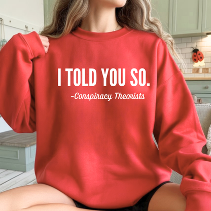 Woman wearing a red sweatshirt with 'I Told You So. - Conspiracy Theorists'.