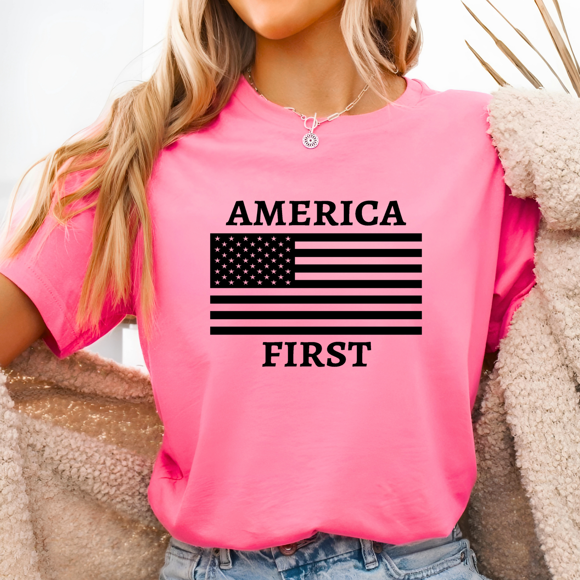 Woman wearing bright pink “America First” shirt with black American flag design