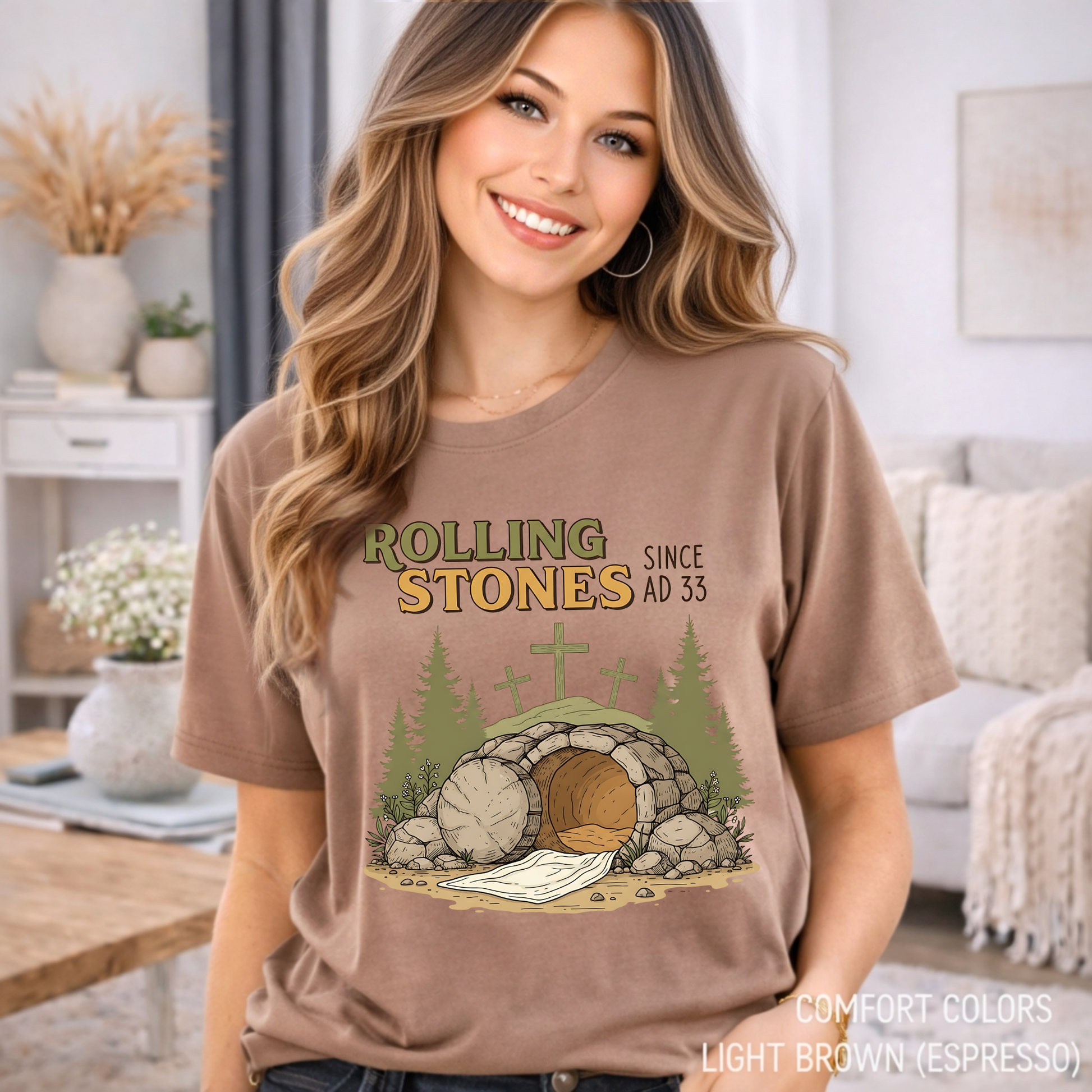 Woman wearing brown Comfort Colors t-shirt with Christian resurrection design in cozy neutral home setting