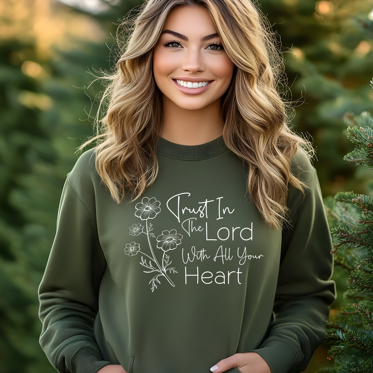 Woman wearing green sweatshirt with floral graphic and “Trust in the Lord With All Your Heart” text.