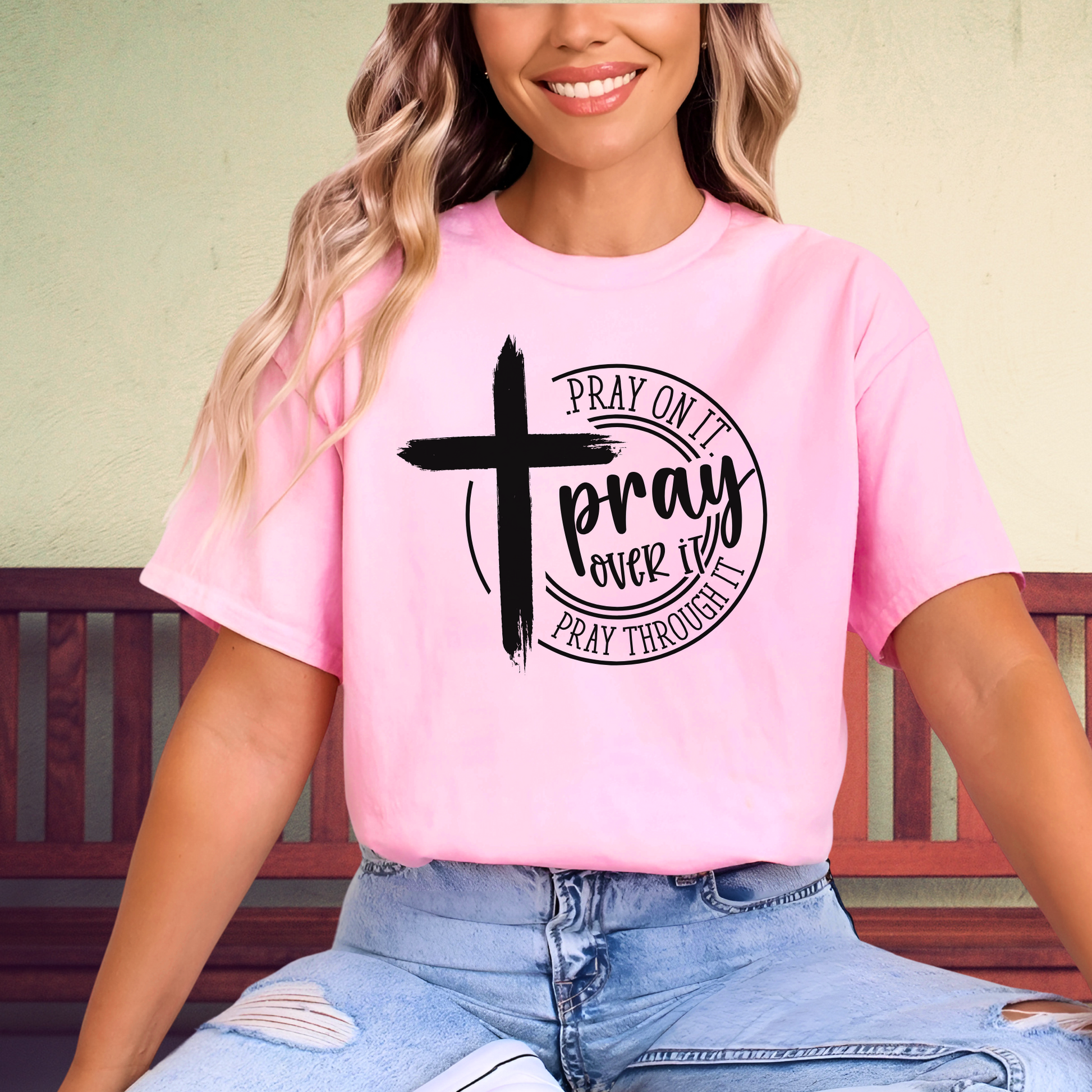 Woman wearing light Pink T-shirt with black cross graphic and inspirational pray wording.