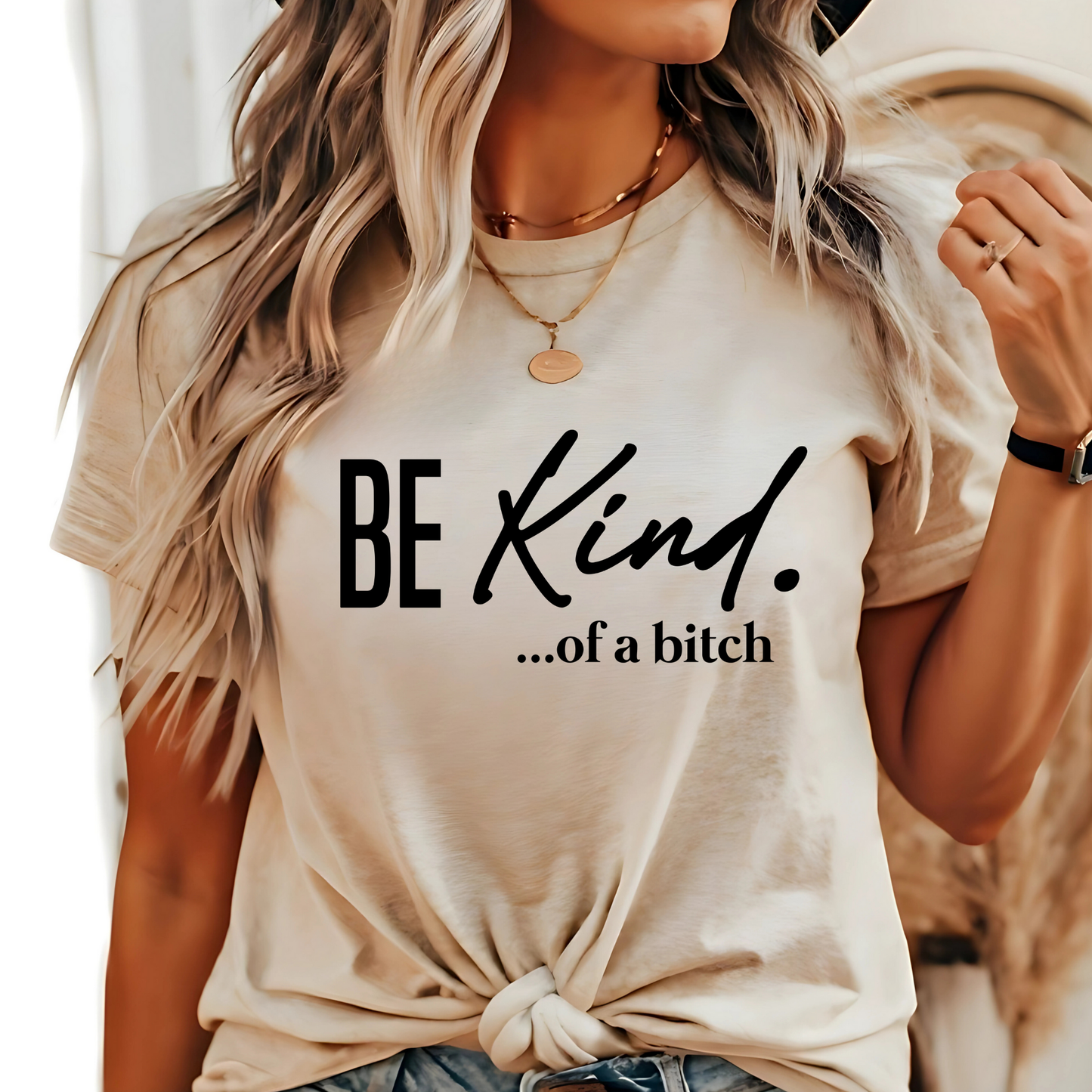 Woman wearing natural beige shirt with “Be Kind…of a bitch” design in black fontt
