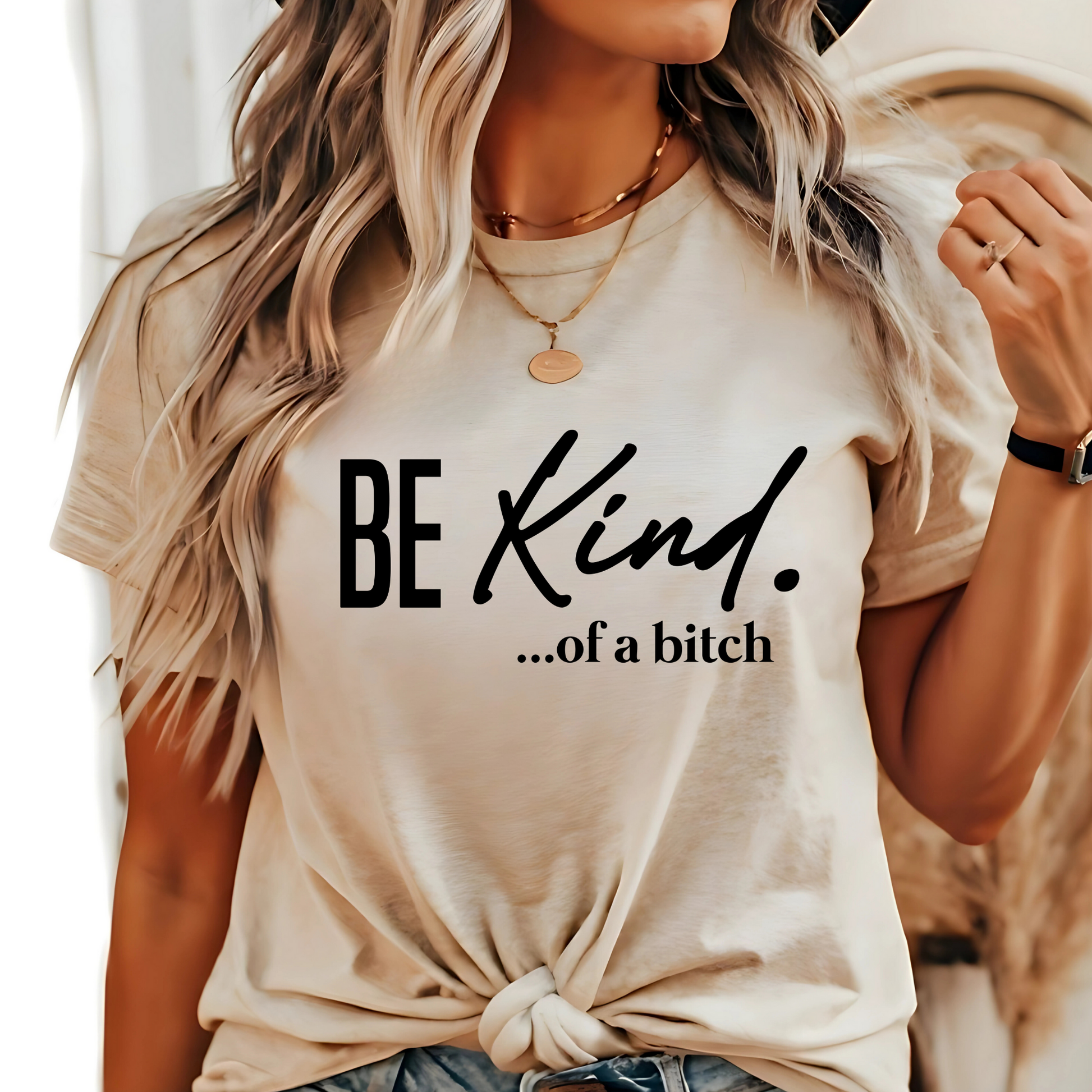 Woman wearing natural beige shirt with “Be Kind…of a bitch” design in black fontt
