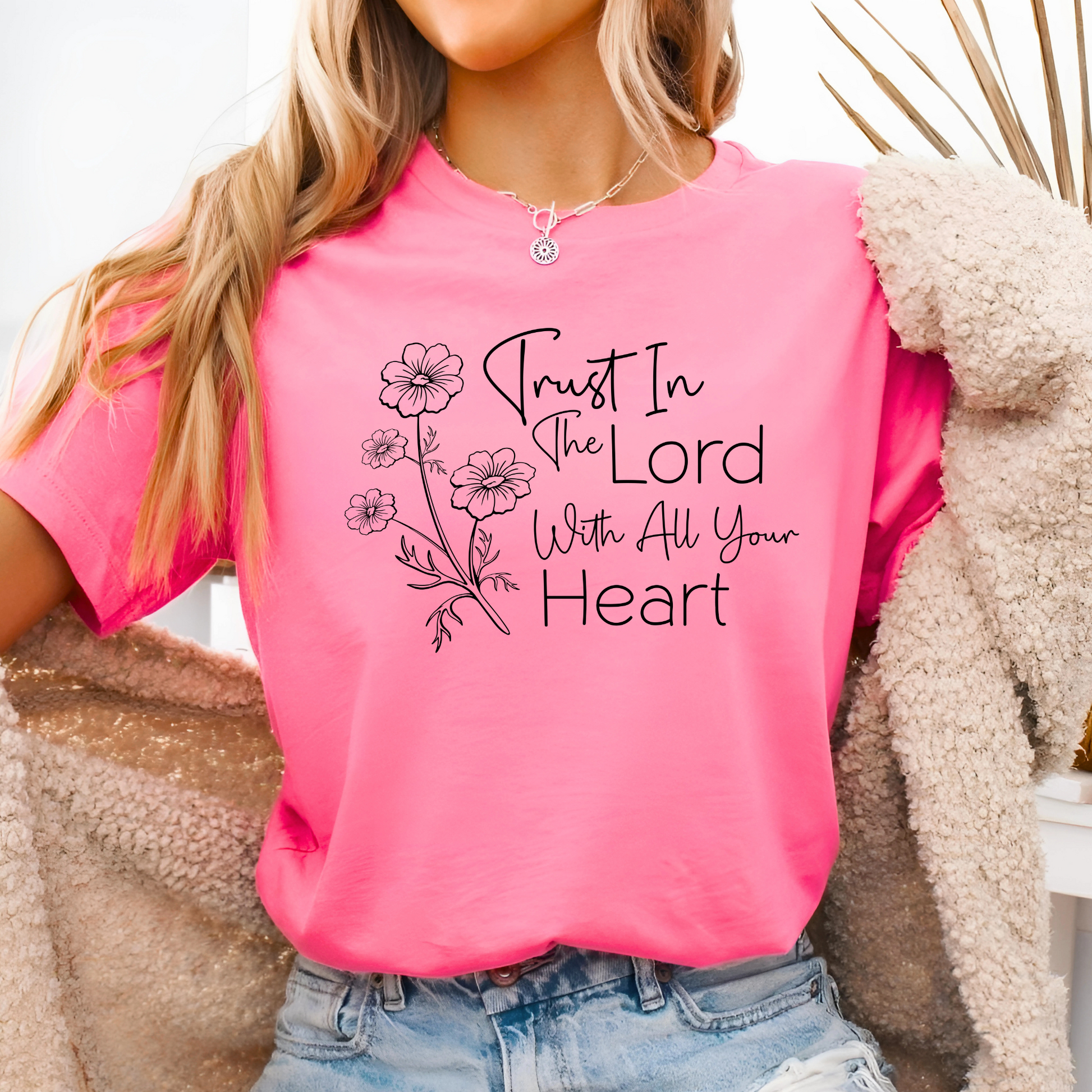Woman wearing pink T-shirt with floral graphic and “Trust in the Lord With All Your Heart” text.