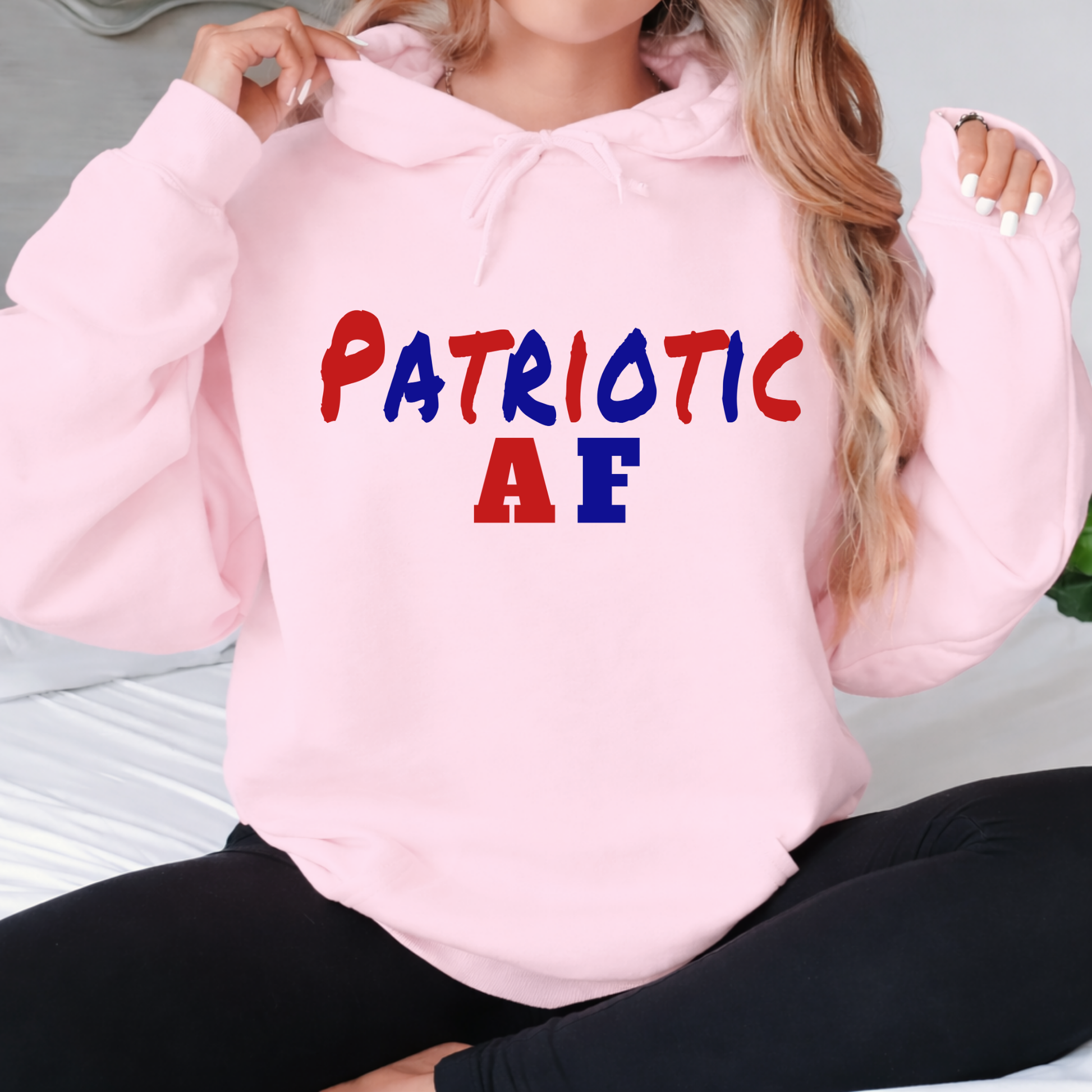 Woman wearing pink patriotic AF hoodie with red white and blue text