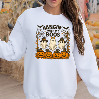 Woman in a white Hangin’ With My Boos sweatshirt with ghost and pumpkin design. Perfect cozy unisex pullover for fall, styled in a pumpkin patch setting.
