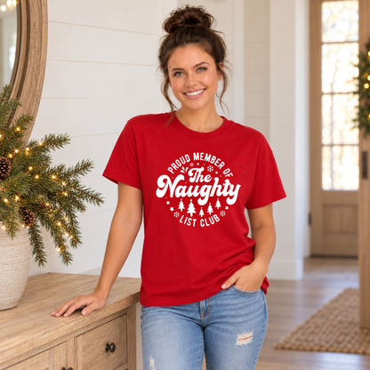 Woman wearing a red T-shirt with a white Proud Member of the Naughty List Club design in a bright holiday entryway.