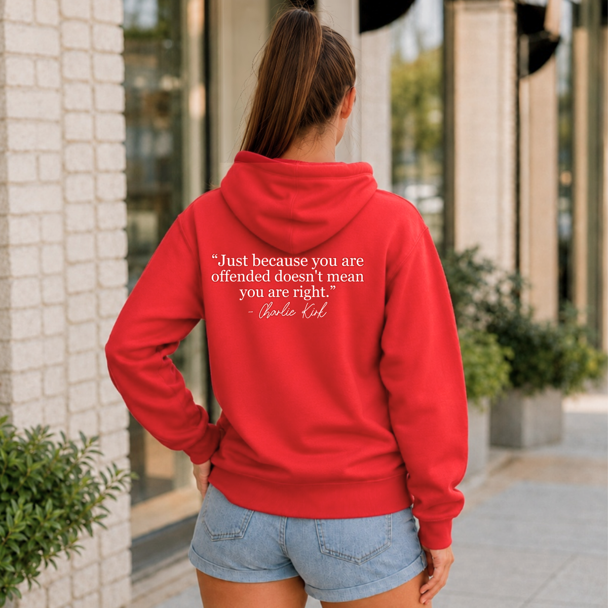 Back view of a woman wearing a red hoodie with a white quote graphic.