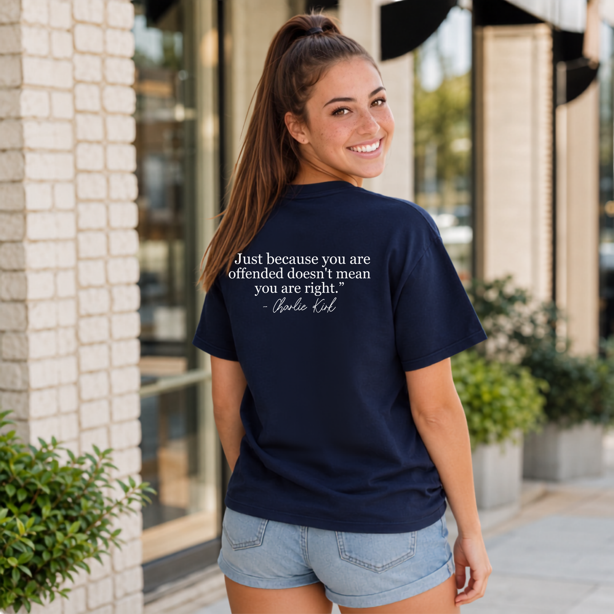 Back view of a woman wearing a navy T-shirt with a white quote graphic.