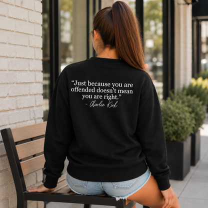 Back view of a woman seated outside in a black crewneck sweatshirt with a white quote graphic.