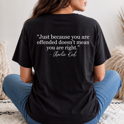 Back view of a woman in a black T-shirt with a white quote graphic, seated on outdoor steps.