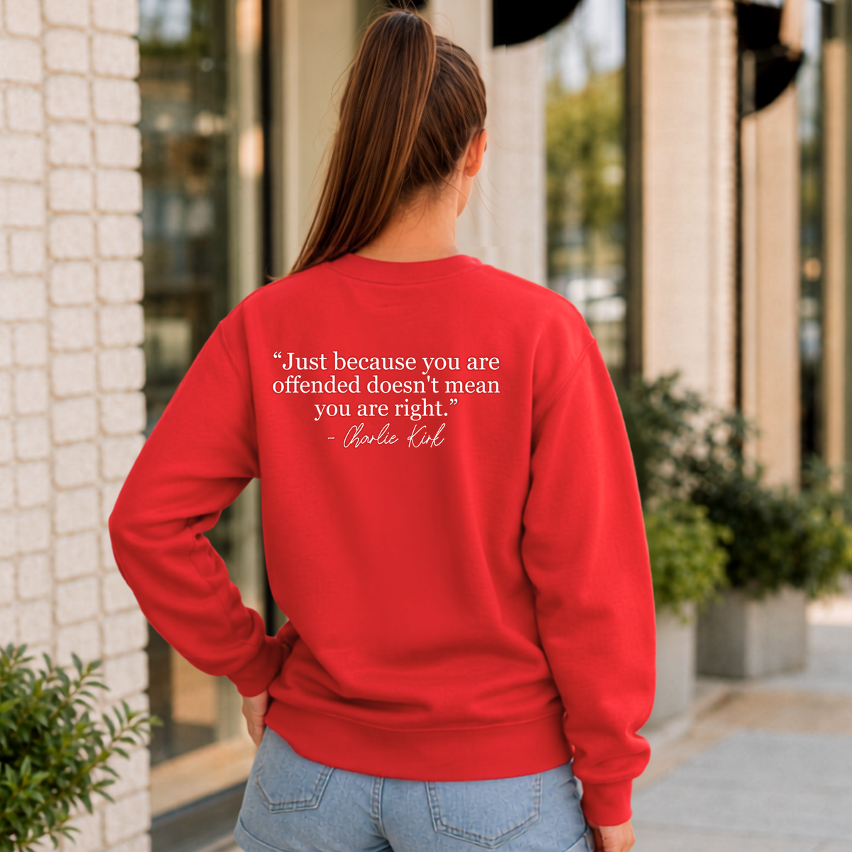 Back view of a woman wearing a red crewneck sweatshirt with a white quote graphic.