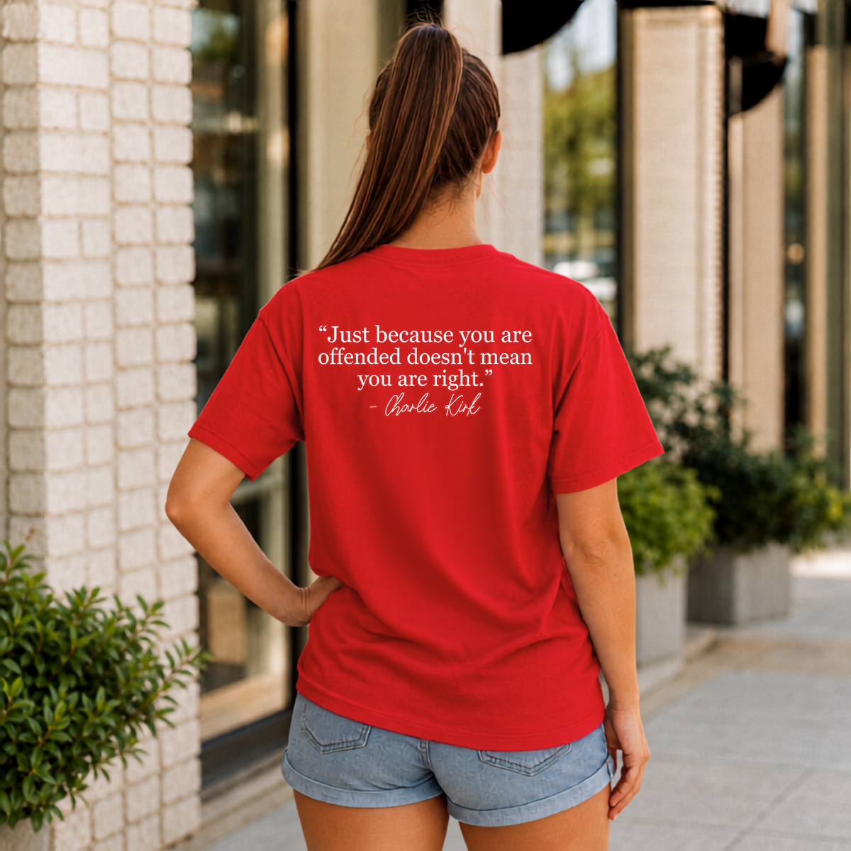 Back view of a woman wearing a red T-shirt with a white quote graphic.
