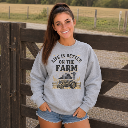 Woman in a sports gray Life Is Better on the Farm sweatshirt standing at a wooden farm gate.