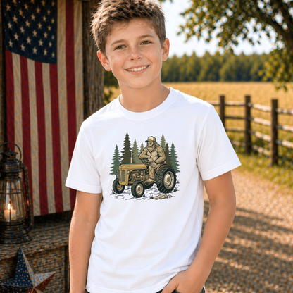 Youth model wearing a white T-shirt with a woodland tractor graphic.