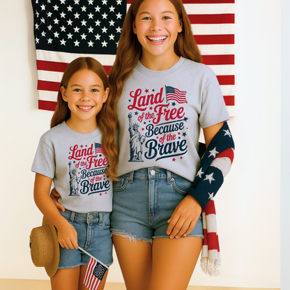 Young girl in gray 4th of July tee holding an American flag and smiling

