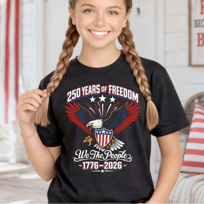 Young girl wearing a black t-shirt with a patriotic design, sitting in a room with American flag decor.