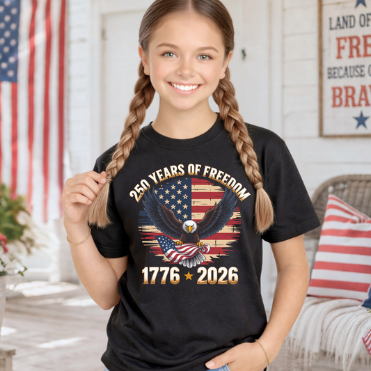 Young girl wearing a black America 250 Years of freedom t-shirt with a patriotic design, standing in a room with American flags.