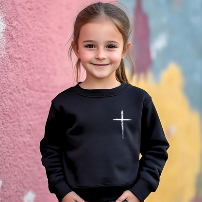Young girl wearing a black 'Jesus Has My Back' youth sweatshirt with a cross design,