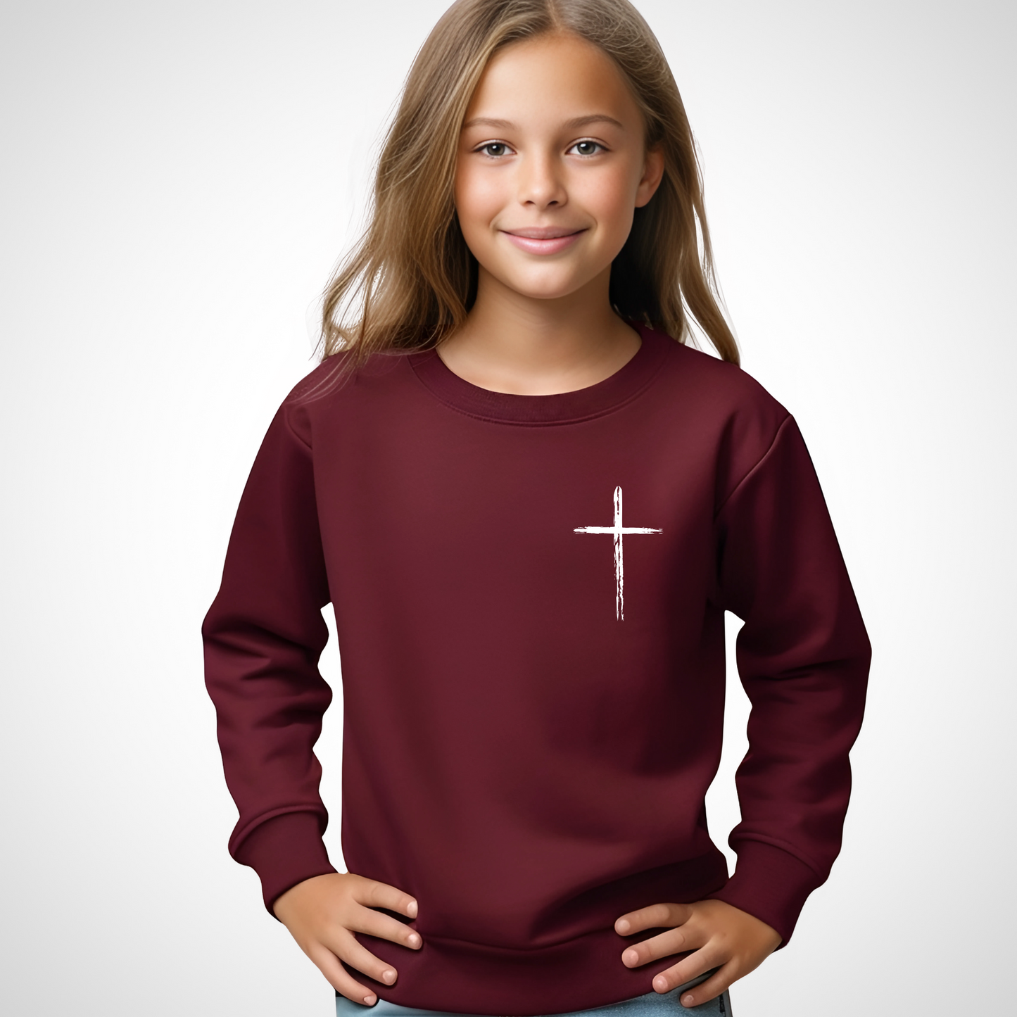 Young girl wearing a maroon 'Jesus Has My Back' youth sweatshirt with a cross design