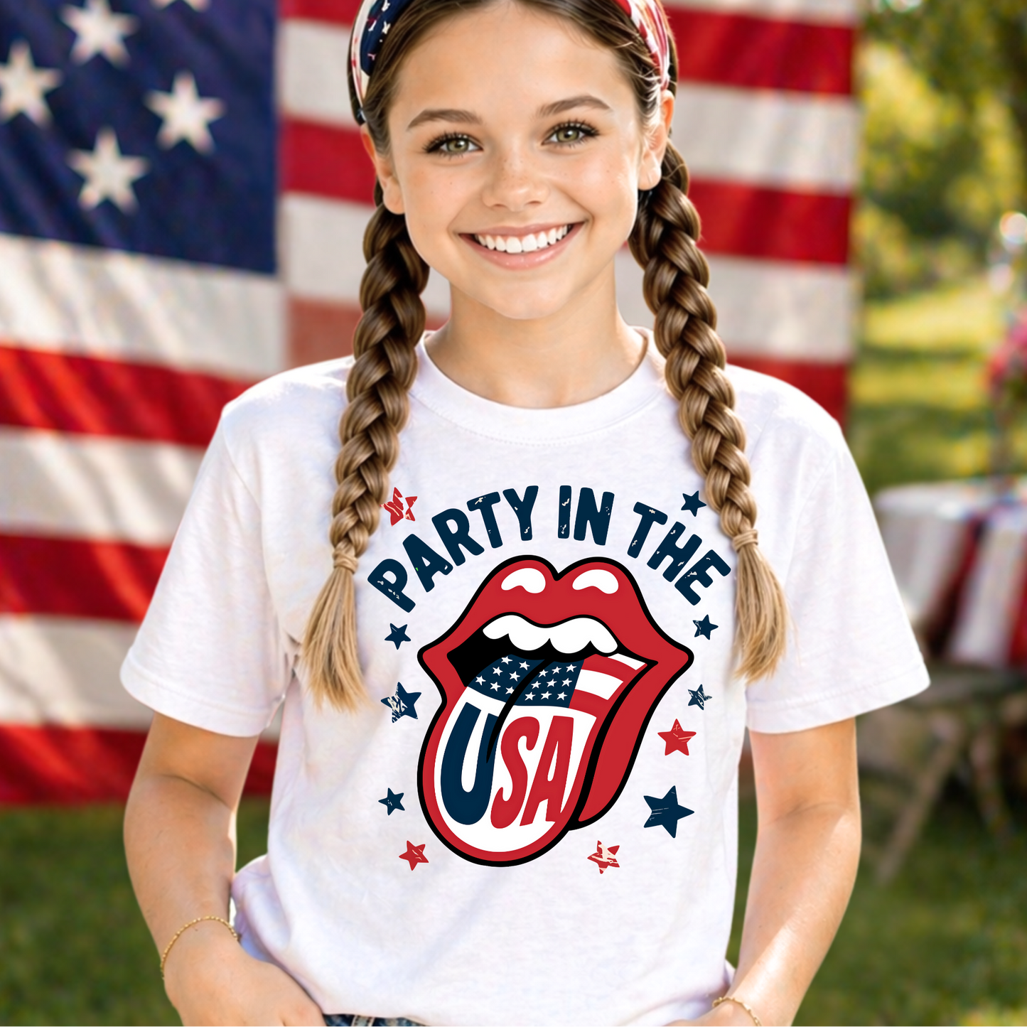 Young girl wearing a 'Party in the USA' t-shirt with an American flag design, standing in front of an American flag.