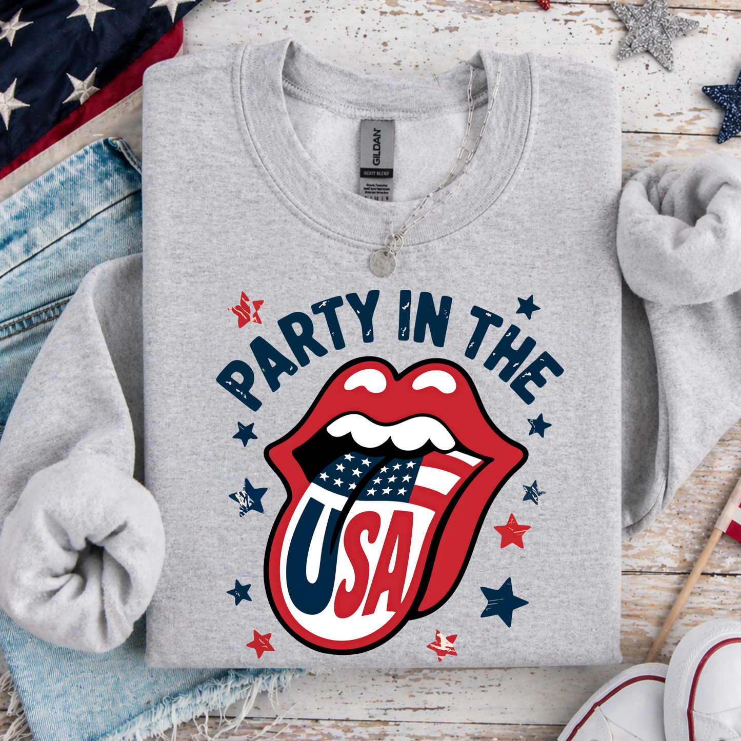Gray sweatshirt with 'Party in the USA' design on a wooden surface with festive decorations.
