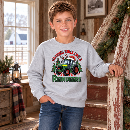 Boy wearing a sports gray Nothing Runs Like a Reindeere sweatshirt by a farmhouse staircase decorated with greenery.