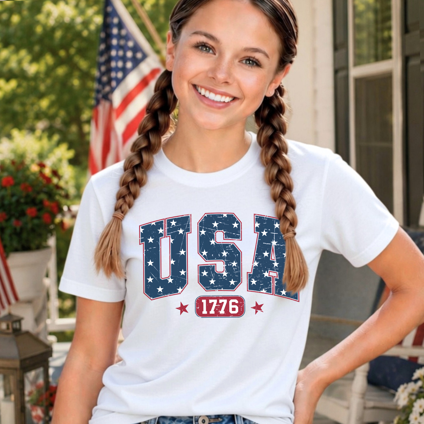 Girl wearing a white t-shirt with 'USA 1776' design, standing outdoors.