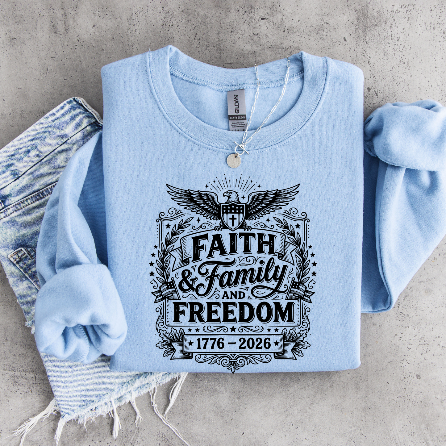 Light blue sweatshirt with 'Faith & Family and Freedom' text on a concrete surface