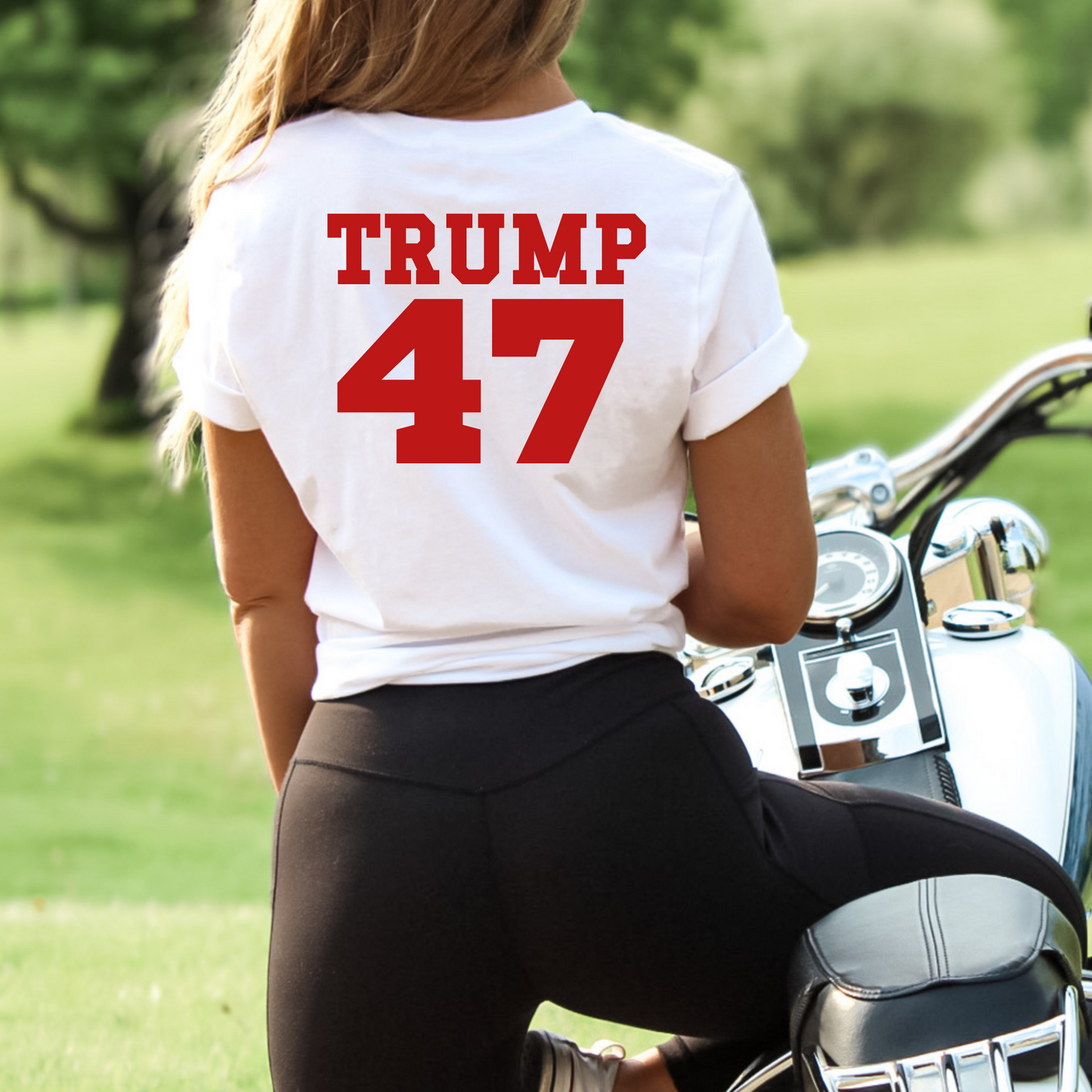 Woman wearing white Trump 47 tee sitting on motorcycle – back view