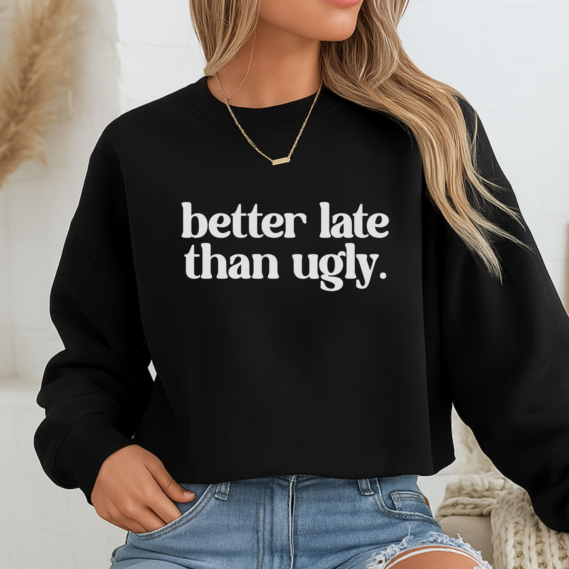 Person wearing a black sweatshirt with 'better late than ugly' text.