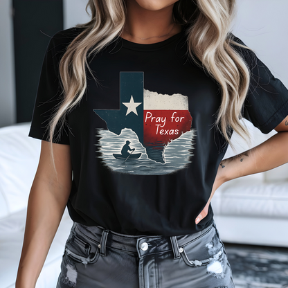Black Pray for Texas T-shirt with a Texas flag silhouette and canoe graphic, designed in a unisex fit for women. Styled with distressed denim for a bold, casual Texas pride outfit.
