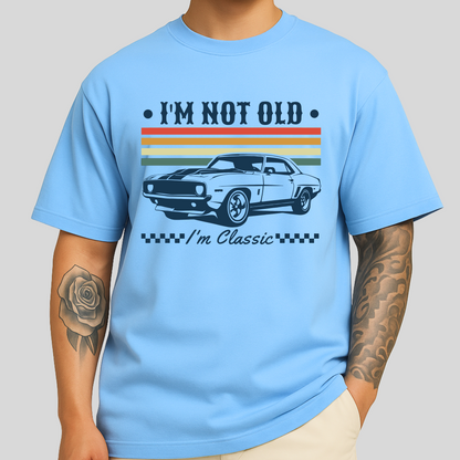 Light blue men’s T-shirt with a bold vintage car graphic and the phrase “I’m Not Old – I’m Classic” across the chest. Design includes retro color stripes and checkered detailing. Ideal shirt for muscle car fans and classic auto enthusiasts.

