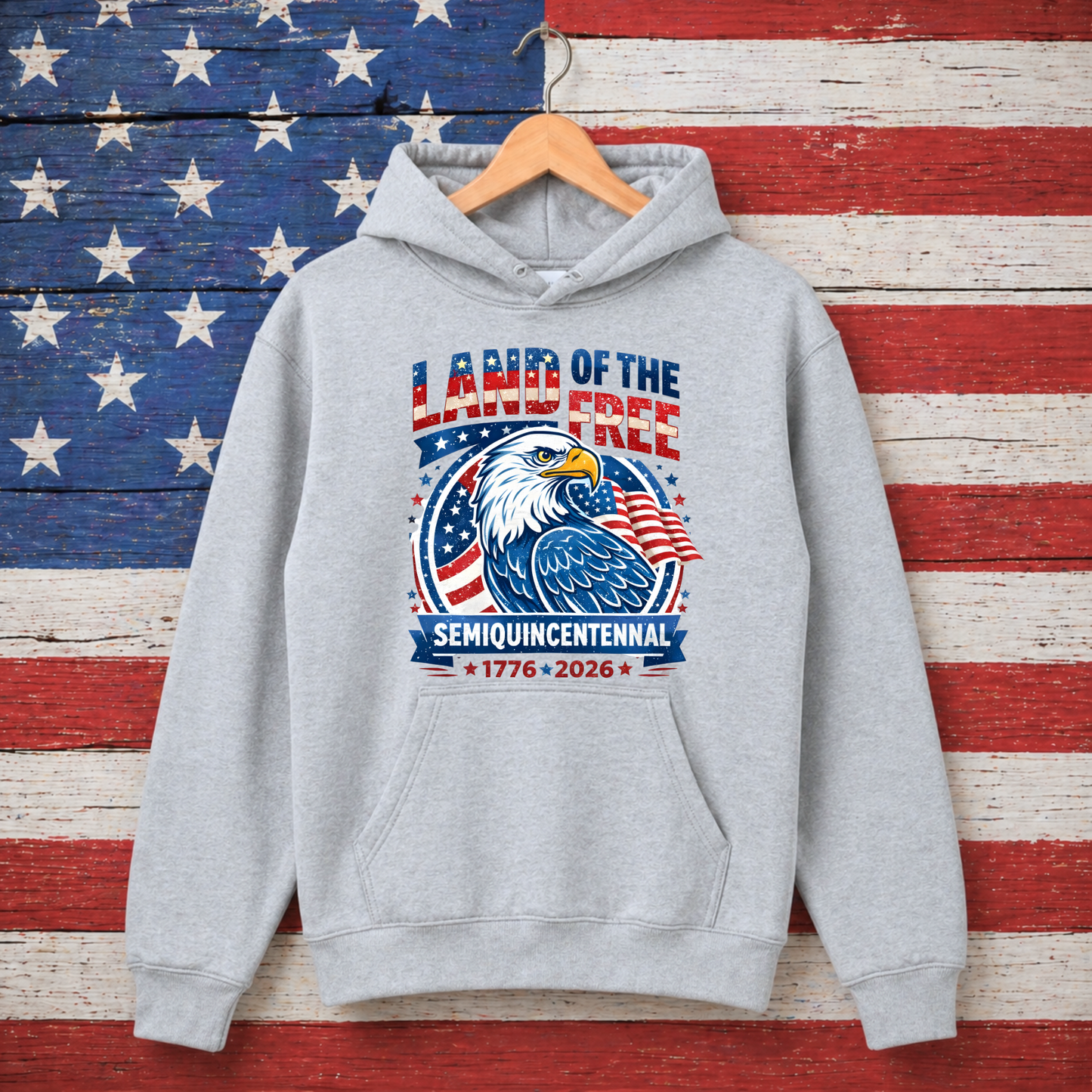 Gray hoodie with 'Land of the Free' design on a wooden background resembling the American flag.