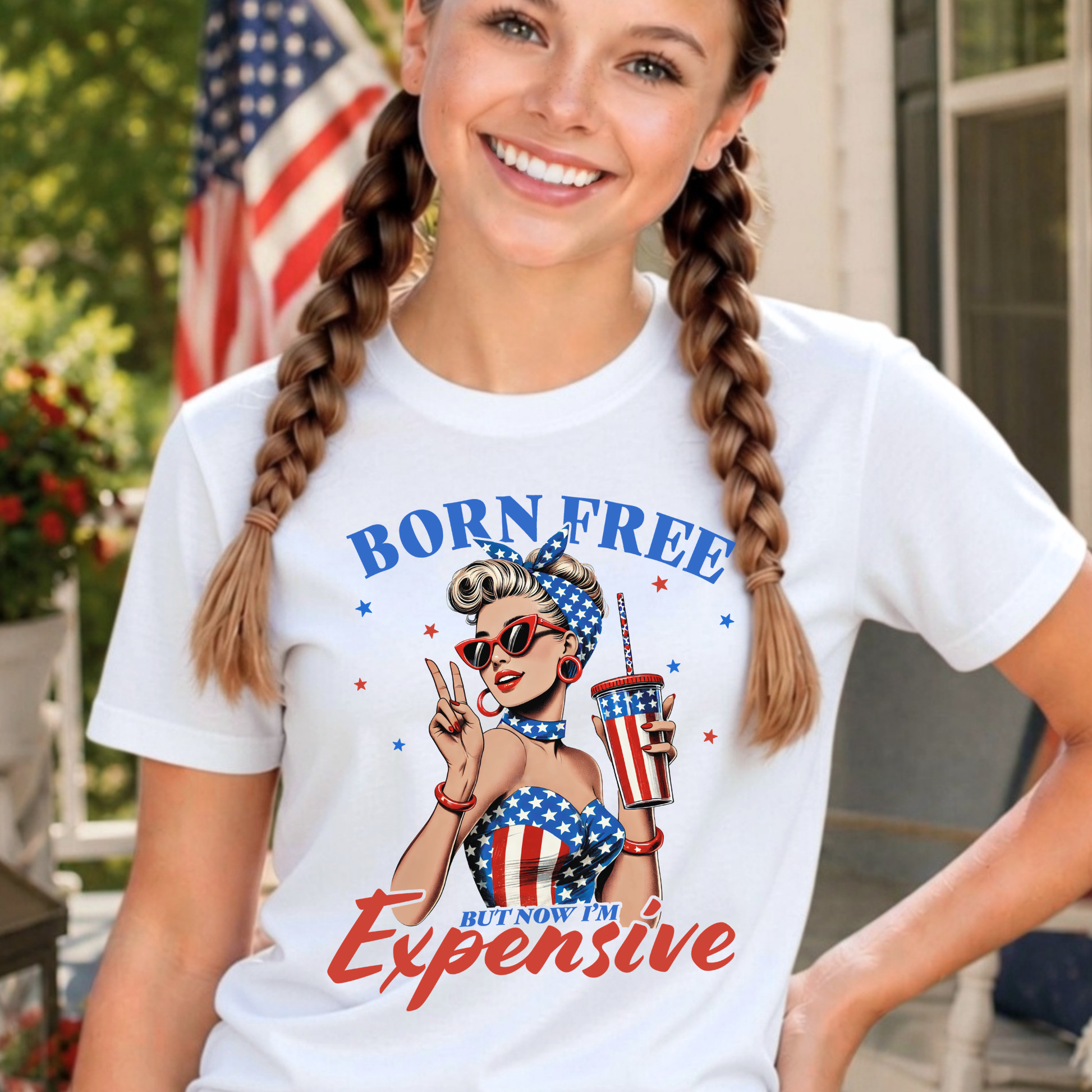 Youth patriotic 4th of July shirt featuring “Born Free But Now I’m Expensive” retro Americana graphic on white tee with braided hairstyle model