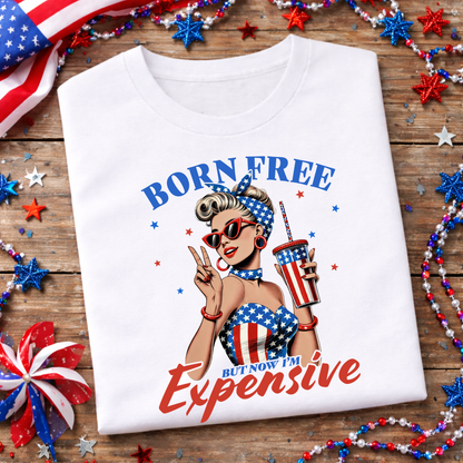 White t-shirt with a graphic design of a woman holding a cup, surrounded by American flag decorations on a wooden surface.