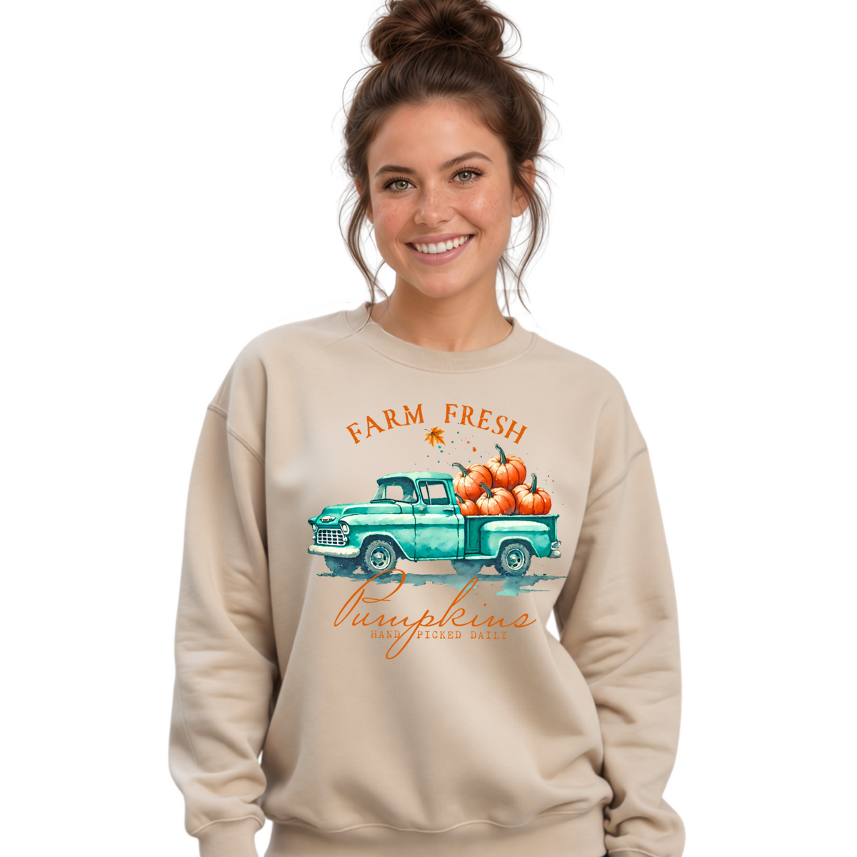 Woman wearing a sand sweatshirt with a vintage teal truck and Farm Fresh Pumpkins design on a white background.