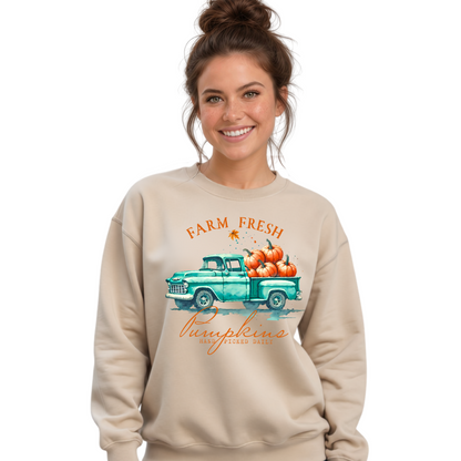 Woman wearing a sand sweatshirt with a vintage teal truck and Farm Fresh Pumpkins design on a white background.