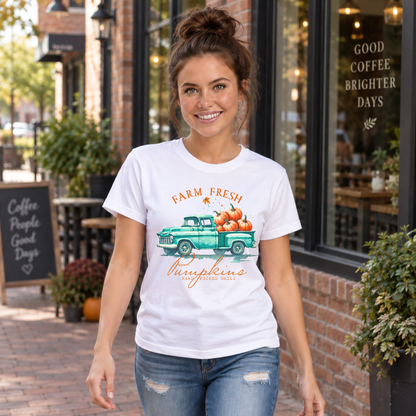 Woman in a white T-shirt with a vintage teal pumpkin truck and Farm Fresh Pumpkins design walking outside a cafe.