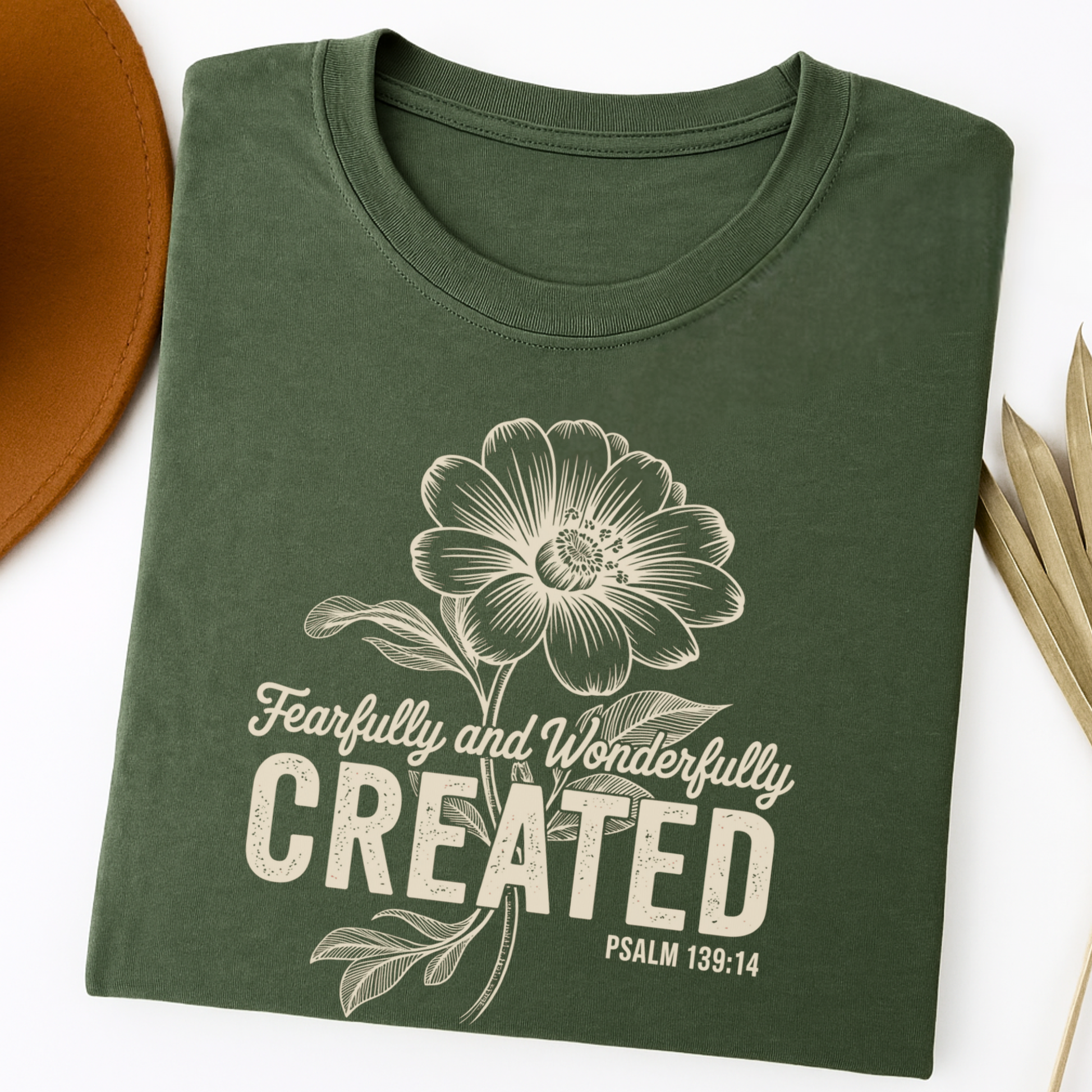 Green t-shirt with floral design and 'Fearfully and Wonderfully Created' text on a white background
