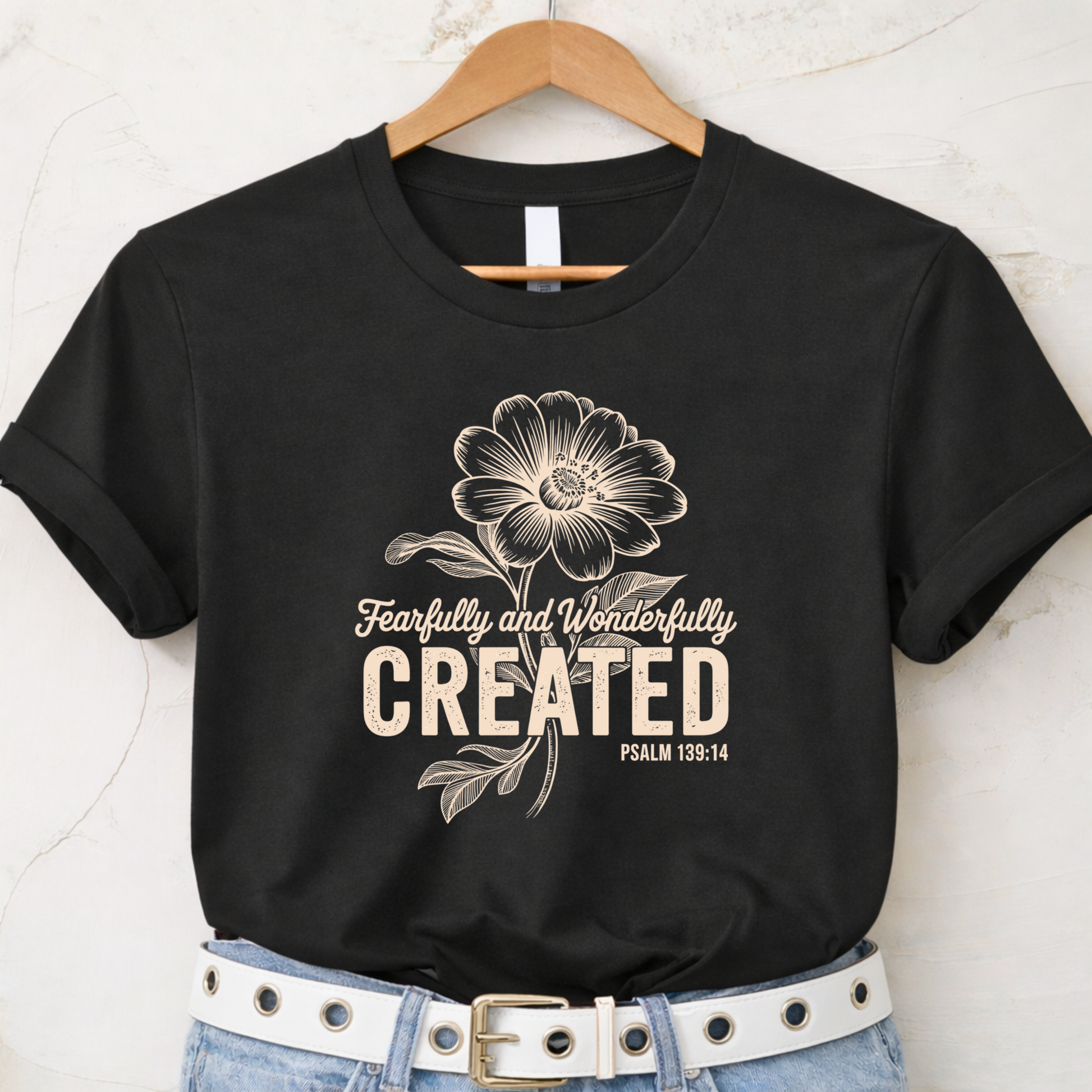 Black t-shirt with Fearfully and Wonderfully Created floral design displayed on hanger