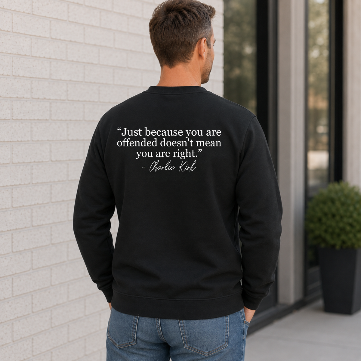 Back view of a man wearing a black crewneck sweatshirt with a white quote graphic.